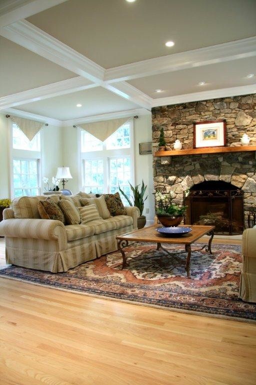Modelo de sala de estar abierta clásica grande con paredes beige, suelo de madera clara, todas las chimeneas y marco de chimenea de piedra
