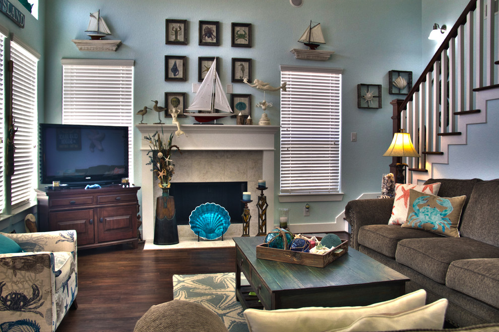Mittelgroßes, Offenes Maritimes Wohnzimmer mit blauer Wandfarbe, braunem Holzboden, Kamin, gefliester Kaminumrandung und freistehendem TV in Houston