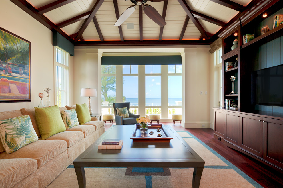 Immagine di un soggiorno tropicale con pareti beige, parquet scuro e parete attrezzata