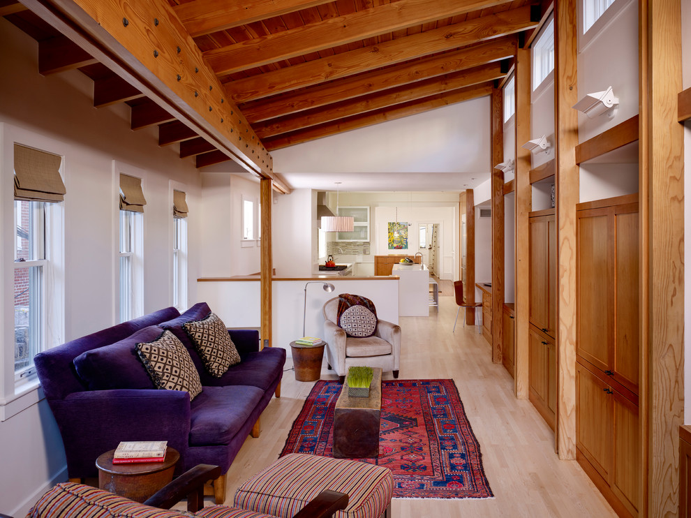 Foto de sala de estar abierta urbana con paredes blancas, suelo de madera clara y televisor retractable