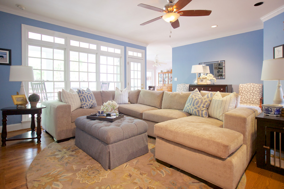 Modelo de sala de estar abierta costera de tamaño medio sin chimenea con paredes azules, suelo de madera clara y suelo marrón