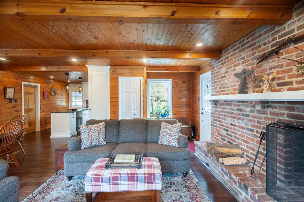 Diseño de sala de estar abierta clásica renovada grande con suelo de madera oscura, todas las chimeneas, marco de chimenea de ladrillo, televisor en una esquina y suelo marrón