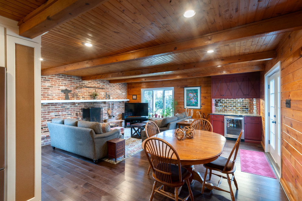 Cette image montre une grande salle de séjour traditionnelle ouverte avec parquet foncé, une cheminée standard, un manteau de cheminée en brique, un téléviseur d'angle et un sol marron.