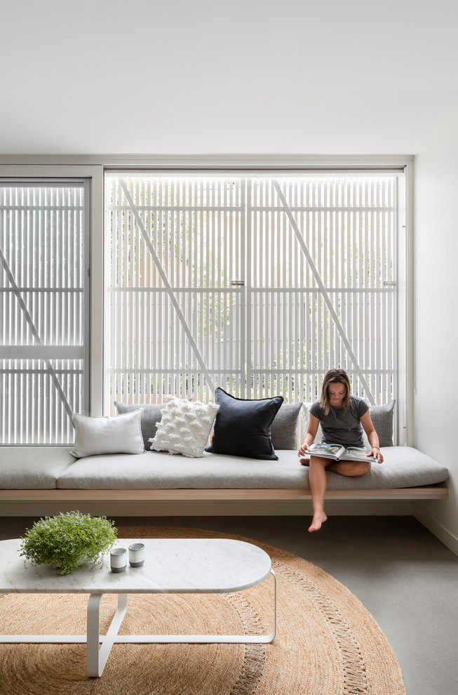 Nordisches Wohnzimmer mit weißer Wandfarbe, Betonboden und grauem Boden in Melbourne