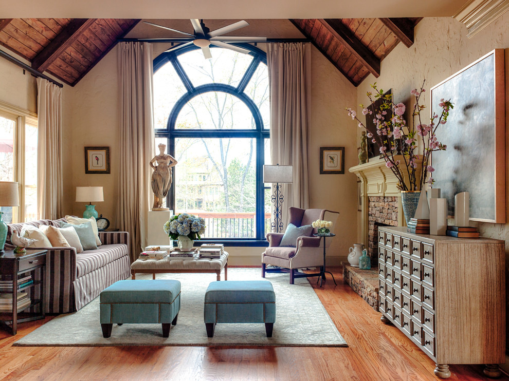 Ejemplo de sala de estar clásica de tamaño medio con paredes beige, suelo de madera en tonos medios, todas las chimeneas, marco de chimenea de piedra, televisor colgado en la pared y alfombra
