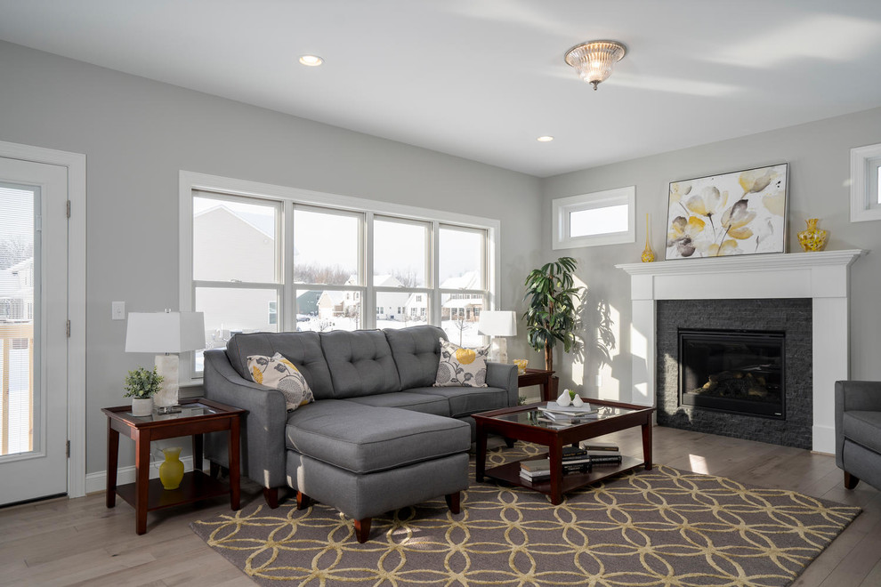 Foto de sala de estar abierta clásica con paredes beige, suelo de madera clara, todas las chimeneas, marco de chimenea de piedra y suelo multicolor