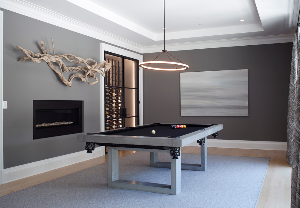 Imagen de sala de estar actual con paredes grises, suelo de madera clara, chimenea lineal y alfombra
