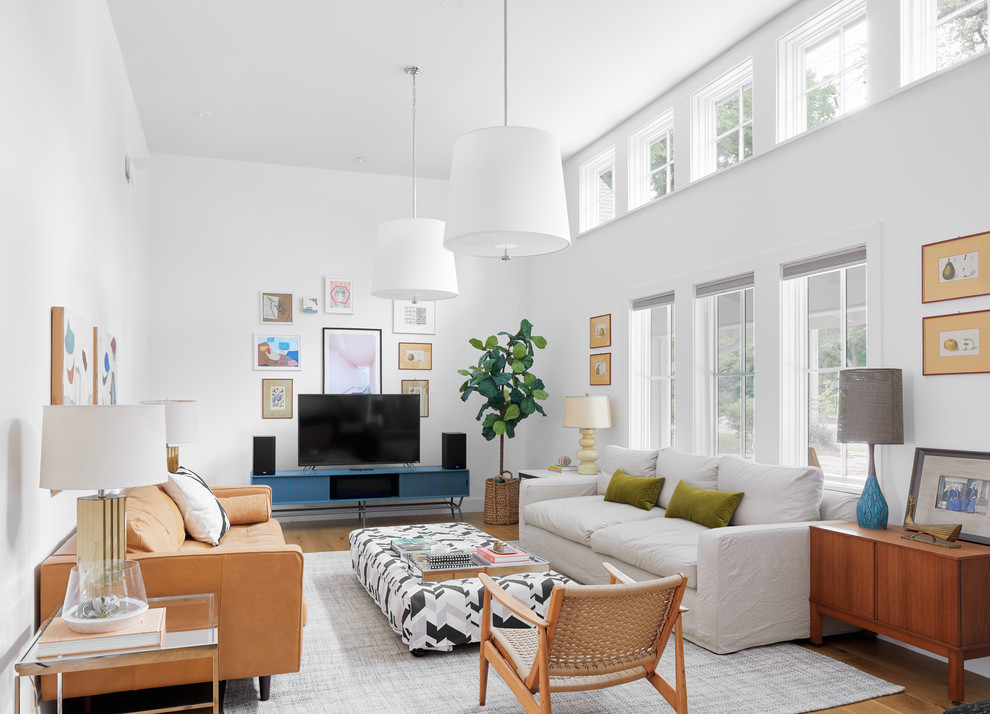 Imagen de sala de estar campestre con paredes blancas, suelo de madera clara y televisor independiente