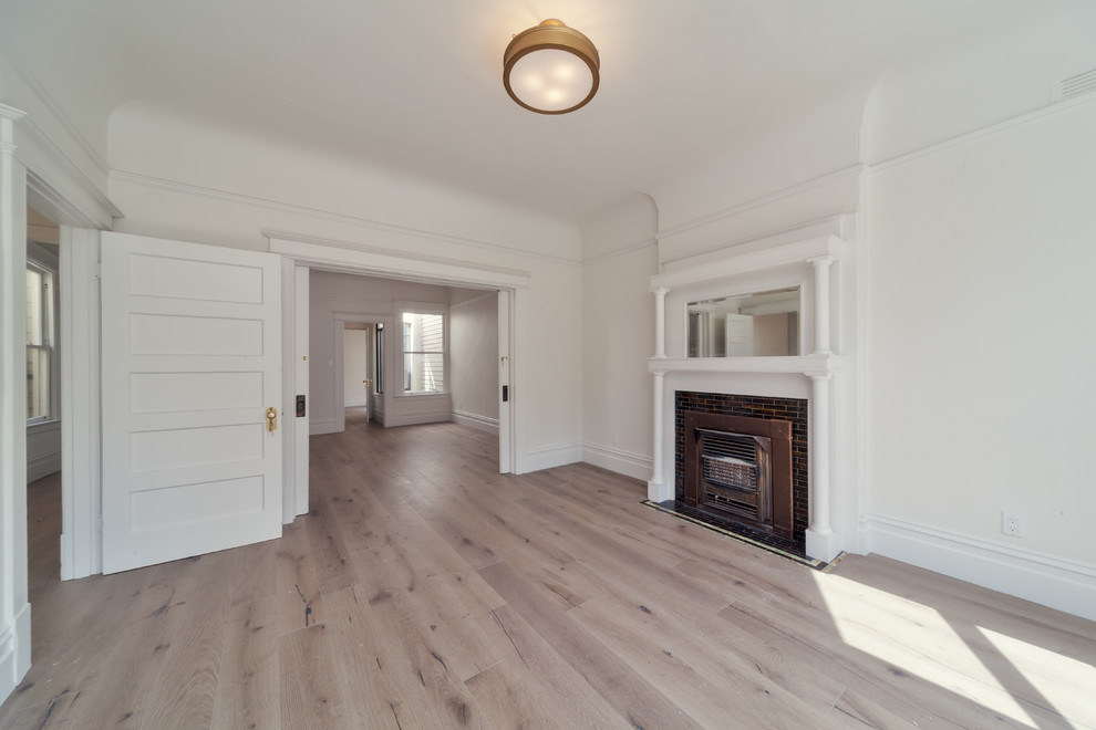 Exemple d'une très grande salle de séjour victorienne avec un mur blanc, parquet clair et un manteau de cheminée en bois.