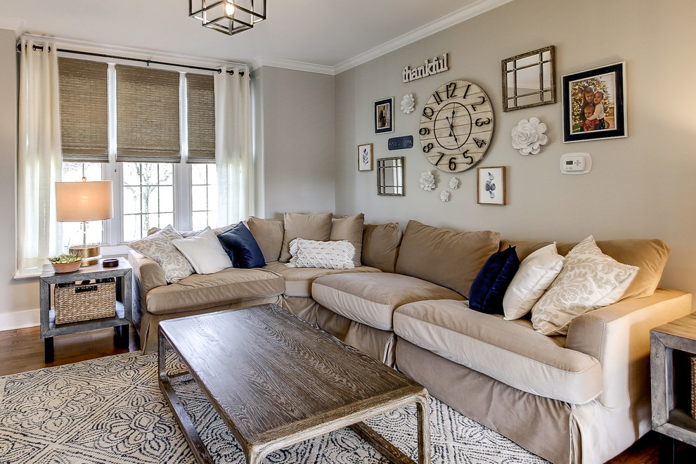 Diseño de sala de estar cerrada tradicional renovada grande sin chimenea con paredes grises, suelo de madera clara, televisor colgado en la pared y suelo marrón