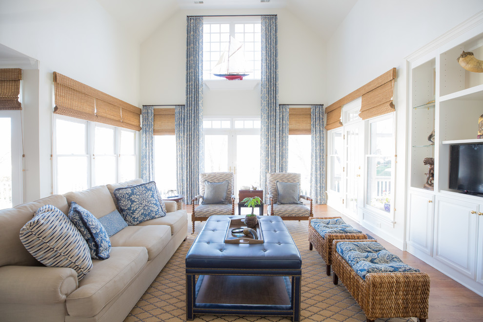 Modelo de sala de estar costera con paredes blancas, suelo de madera en tonos medios y pared multimedia