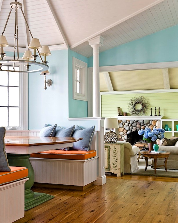 Foto de sala de estar costera grande con suelo de madera en tonos medios y marco de chimenea de piedra