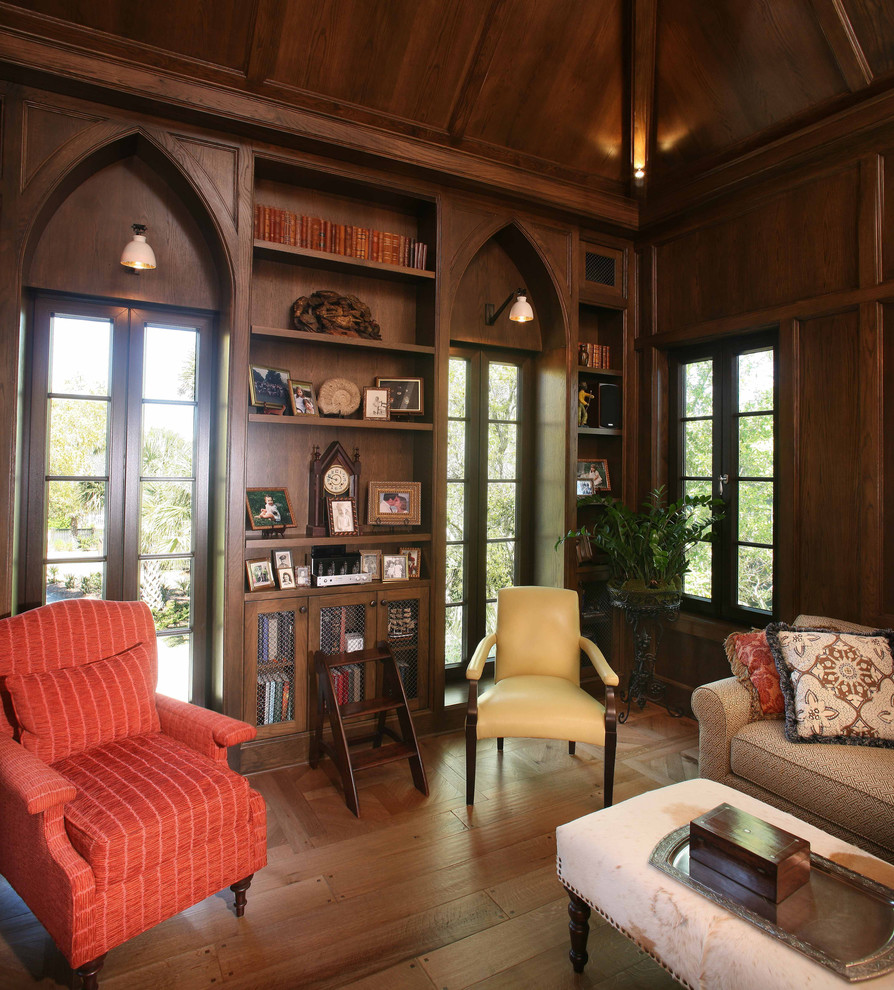На фото: гостиная комната в классическом стиле с с книжными шкафами и полками, коричневыми стенами и паркетным полом среднего тона без камина, телевизора с