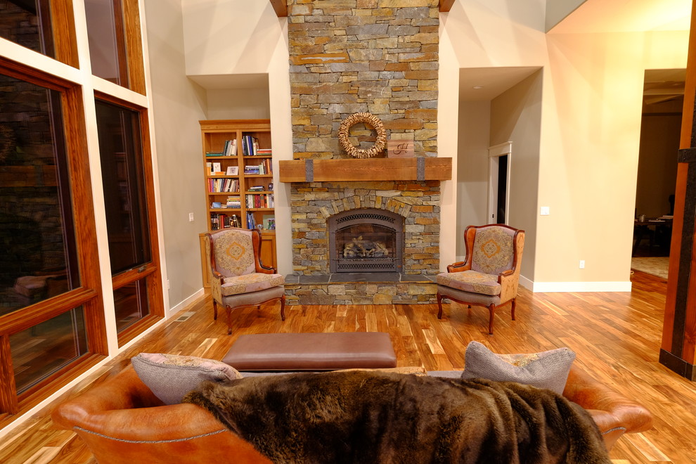 Example of a large arts and crafts open concept medium tone wood floor and brown floor family room design in Sacramento with a standard fireplace, a stone fireplace, beige walls and no tv