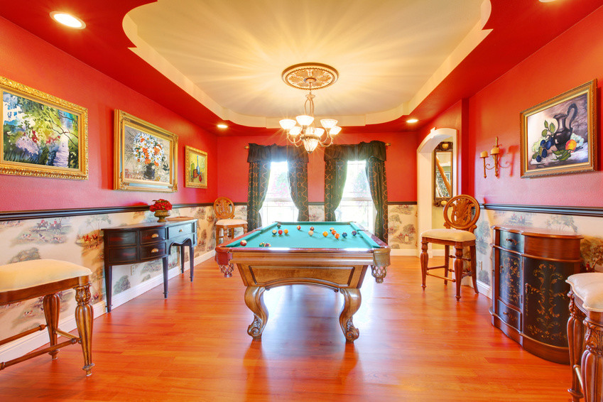Großer, Fernseherloser Stilmix Hobbyraum ohne Kamin, im Loft-Stil mit roter Wandfarbe, braunem Holzboden und Kaminumrandung aus Holz in Miami