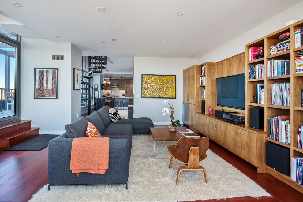 Пример оригинального дизайна: изолированная гостиная комната в современном стиле с белыми стенами, темным паркетным полом, телевизором на стене и красным полом