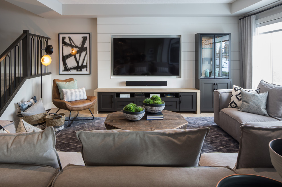 Modelo de sala de estar abierta de estilo de casa de campo grande con paredes grises, suelo laminado, pared multimedia, suelo marrón, bandeja y machihembrado
