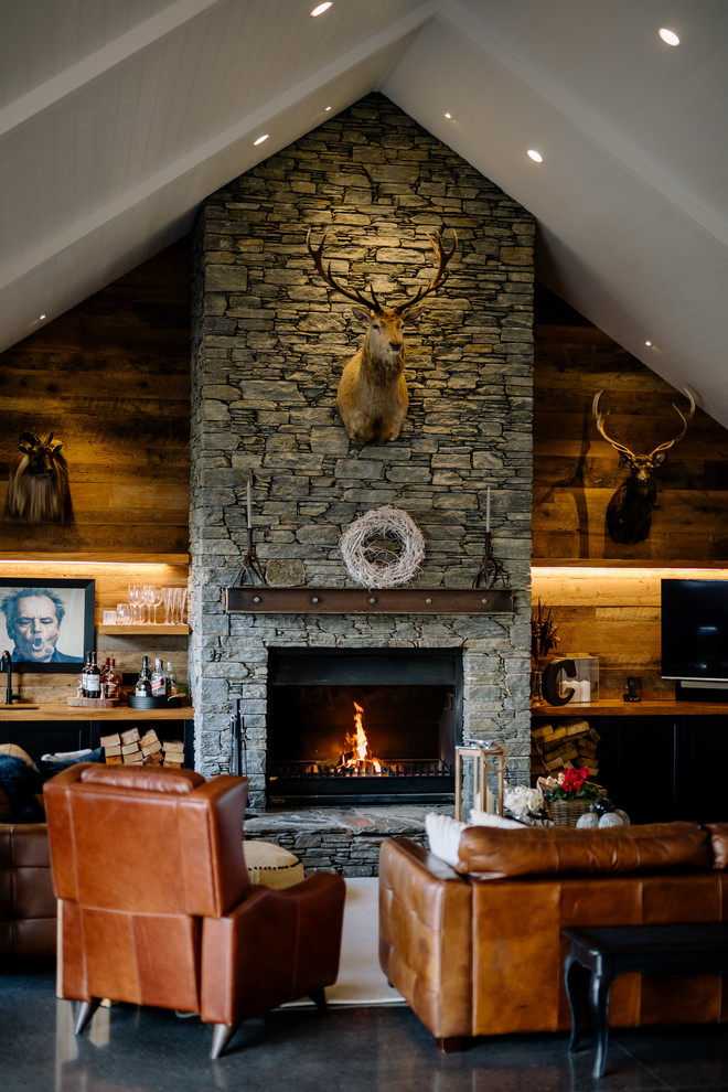 Exemple d'un salon nature ouvert avec un bar de salon, un mur marron, une cheminée standard, un manteau de cheminée en pierre et un sol gris.