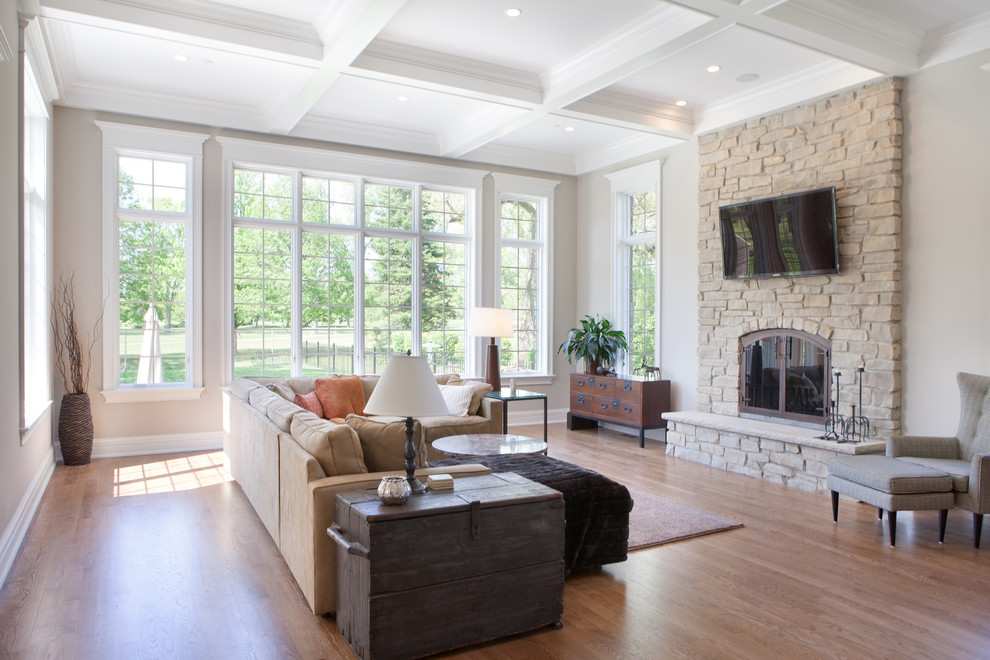 Modelo de sala de estar abierta contemporánea grande con paredes grises, suelo de madera clara, todas las chimeneas, marco de chimenea de piedra y televisor colgado en la pared