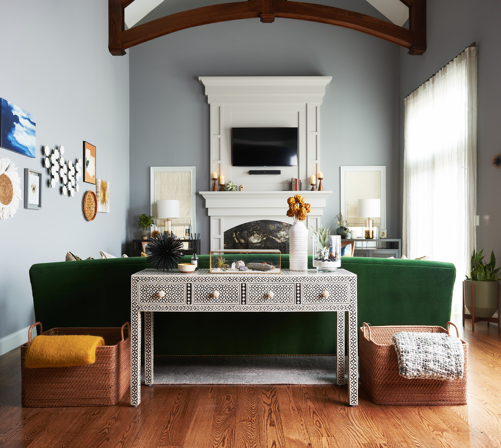 Ejemplo de sala de estar abierta de estilo de casa de campo grande con paredes azules, suelo de madera en tonos medios, todas las chimeneas, marco de chimenea de piedra, televisor colgado en la pared y suelo marrón