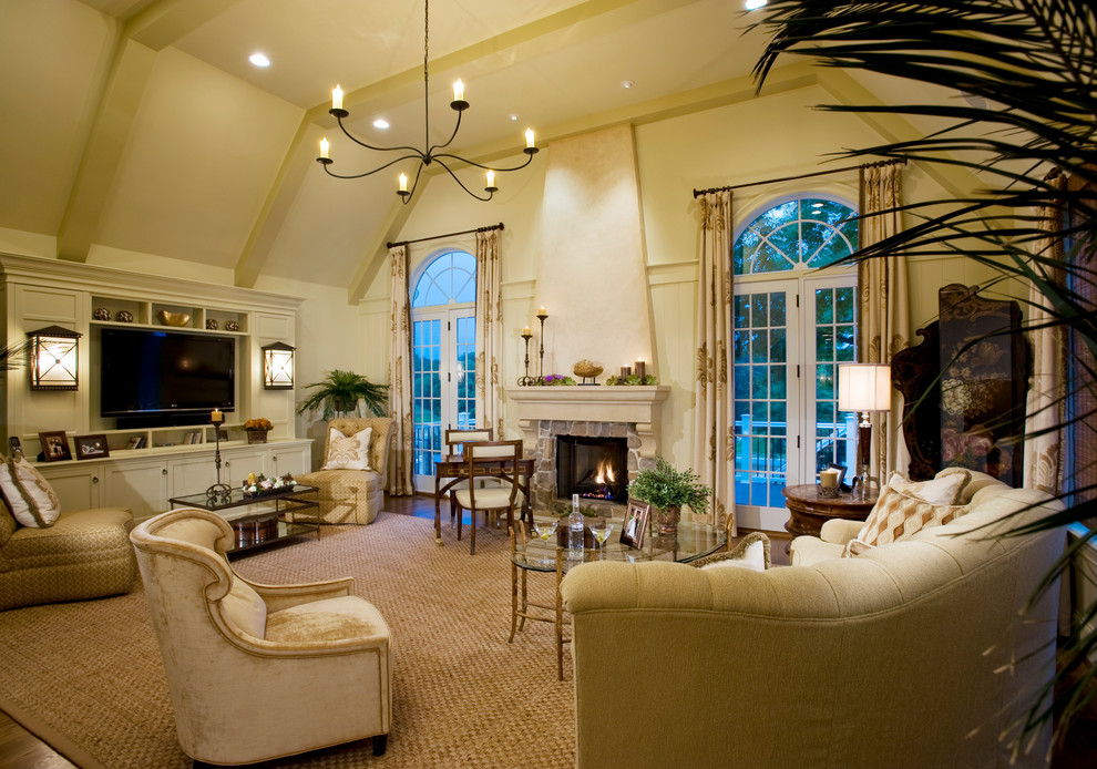 Ejemplo de sala de estar clásica con paredes beige, todas las chimeneas, marco de chimenea de piedra y televisor colgado en la pared