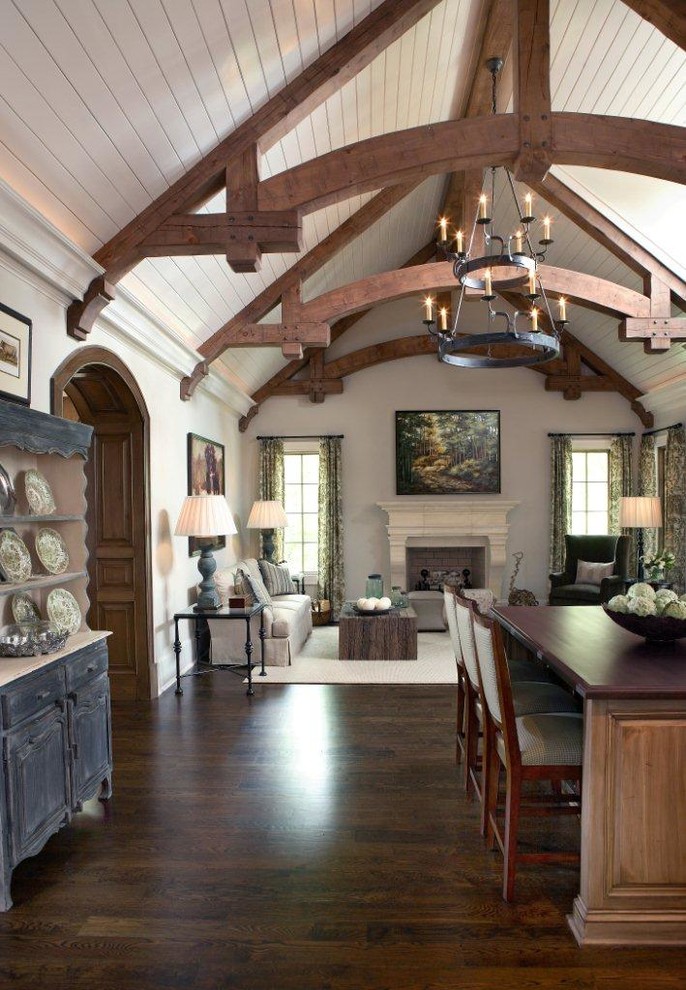 Inspiration for a large mediterranean open plan games room in Atlanta with white walls, dark hardwood flooring, a standard fireplace, a stone fireplace surround, a concealed tv, brown floors and exposed beams.