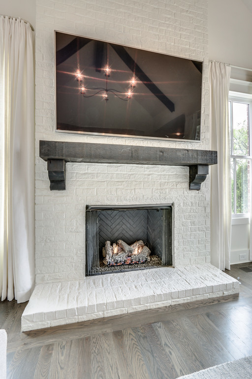Photo of a classic open plan games room in Nashville with white walls, a standard fireplace and a plastered fireplace surround.