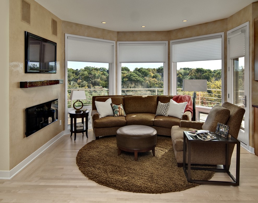 Exempel på ett modernt vardagsrum, med beige väggar, ljust trägolv, en bred öppen spis och en väggmonterad TV