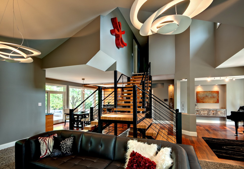 Diseño de sala de estar abierta actual grande sin chimenea con paredes grises, suelo de madera en tonos medios y suelo marrón