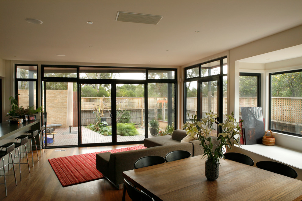 Immagine di un ampio soggiorno minimalista aperto con pareti bianche e pavimento in legno massello medio