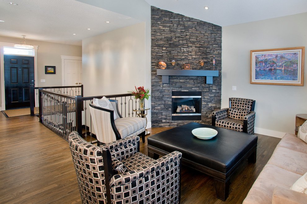 This is an example of a small traditional open plan games room in Calgary with grey walls, medium hardwood flooring, a standard fireplace, a stone fireplace surround and no tv.
