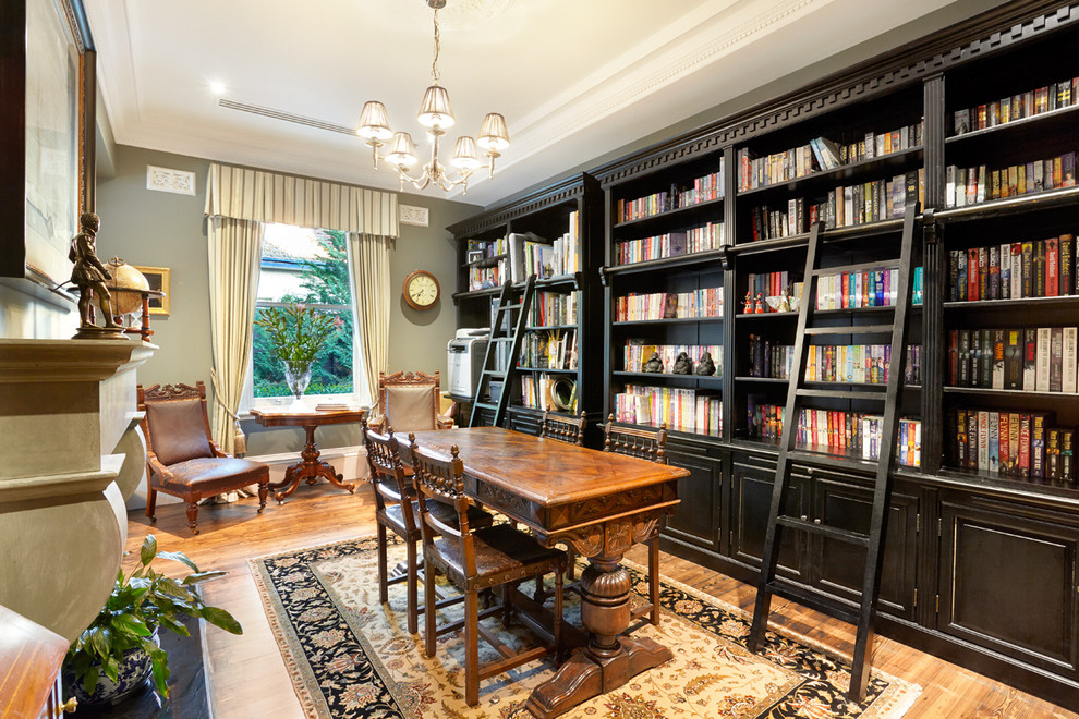 Exemple d'une salle de séjour victorienne de taille moyenne et fermée avec une bibliothèque ou un coin lecture, un mur gris, un sol en bois brun, une cheminée standard, un sol marron et un manteau de cheminée en béton.