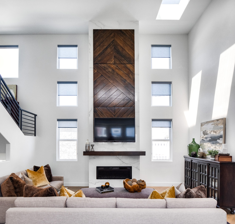 Пример оригинального дизайна: большая открытая гостиная комната в стиле модернизм с белыми стенами, светлым паркетным полом, горизонтальным камином, фасадом камина из камня, телевизором на стене и коричневым полом