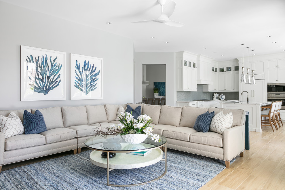 Modelo de sala de estar abierta marinera de tamaño medio con paredes grises, suelo de baldosas de porcelana, televisor colgado en la pared y suelo marrón