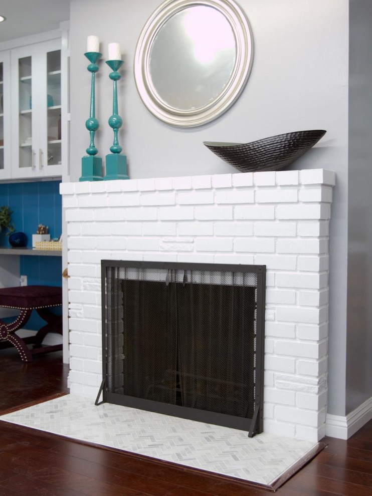 Cette image montre une salle de séjour minimaliste ouverte avec un mur gris, parquet foncé, une cheminée standard, un manteau de cheminée en brique et un téléviseur indépendant.