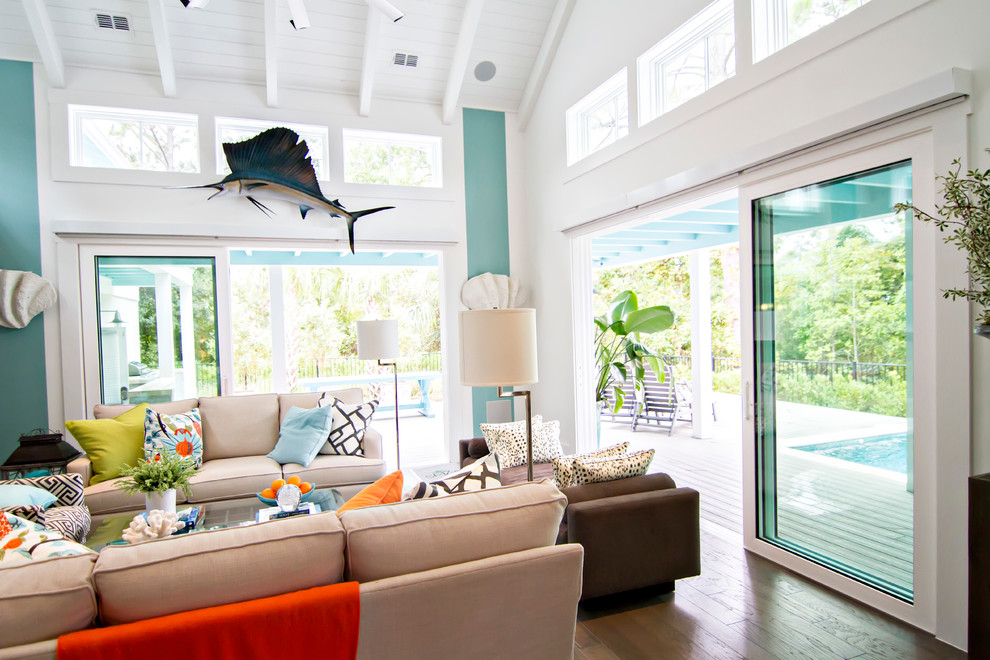 Idee per un grande soggiorno tropicale aperto con pareti blu, pavimento in legno massello medio e TV a parete