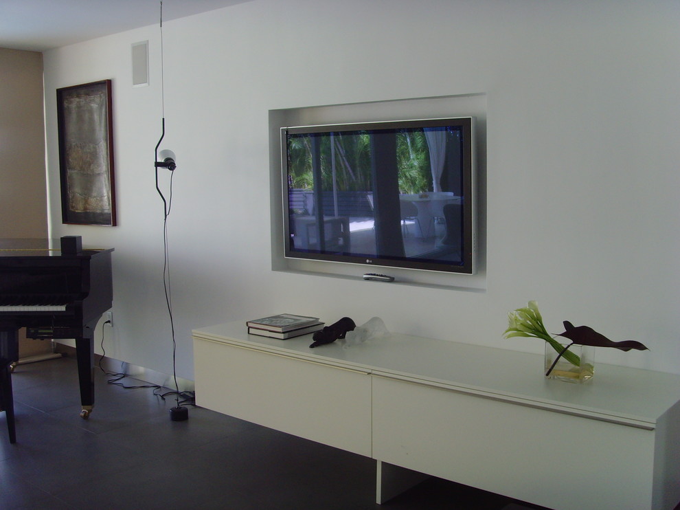 На фото: открытая гостиная комната среднего размера в стиле модернизм с музыкальной комнатой, белыми стенами, бетонным полом, телевизором на стене и серым полом без камина с