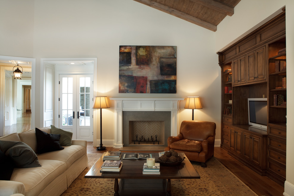 Cette image montre une salle de séjour traditionnelle ouverte avec un mur beige, un sol en bois brun, une cheminée standard et un téléviseur encastré.
