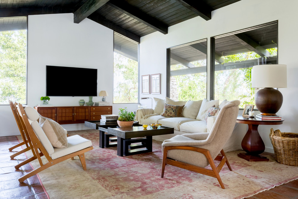 Diseño de sala de estar retro con paredes blancas, suelo de madera en tonos medios, televisor colgado en la pared, suelo marrón y alfombra