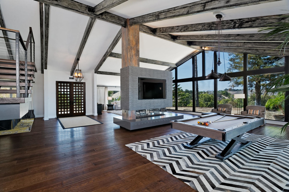 Cette image montre une salle de séjour design avec un mur blanc, parquet foncé, une cheminée double-face et un téléviseur encastré.