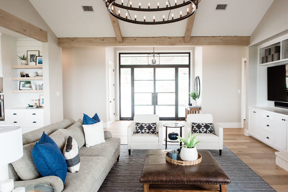 Großes, Offenes Klassisches Wohnzimmer mit grauer Wandfarbe, hellem Holzboden, Kamin, Kaminumrandung aus Stein, TV-Wand und braunem Boden in Austin