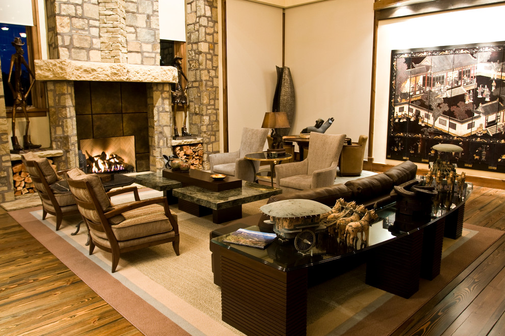 Exemple d'une très grande salle de séjour montagne ouverte avec un mur multicolore, une cheminée standard, un manteau de cheminée en pierre, un téléviseur dissimulé, un sol en bois brun et un sol marron.
