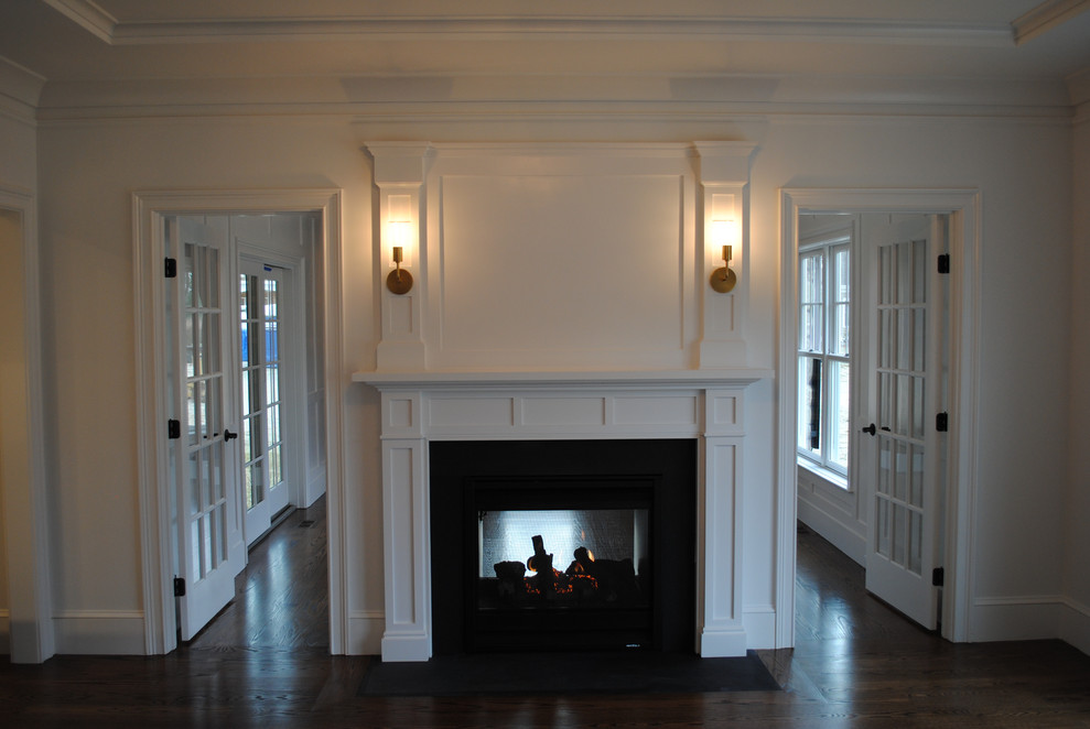Идея дизайна: огромная изолированная гостиная комната в классическом стиле с с книжными шкафами и полками, белыми стенами, темным паркетным полом, двусторонним камином, фасадом камина из дерева и коричневым полом без телевизора