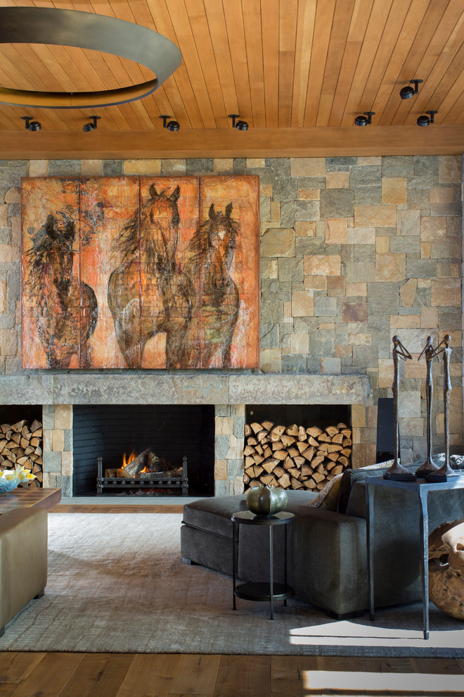 Exemple d'une salle de séjour moderne ouverte et de taille moyenne avec un mur multicolore, un sol en bois brun, une cheminée standard, un manteau de cheminée en pierre, un téléviseur dissimulé et un sol marron.