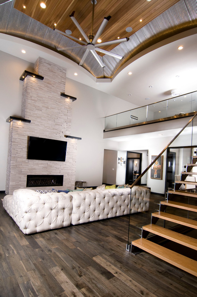 Großes, Offenes Modernes Wohnzimmer mit weißer Wandfarbe, dunklem Holzboden, Gaskamin, Kaminumrandung aus Stein, TV-Wand und braunem Boden in Cedar Rapids