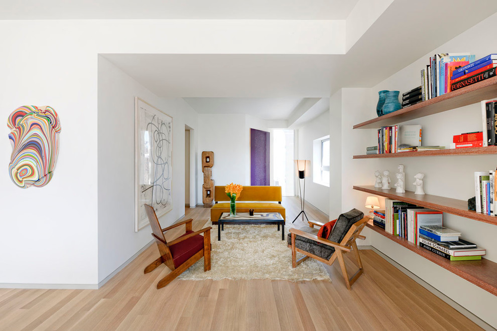 Modelo de sala de estar con biblioteca contemporánea sin chimenea y televisor con suelo de madera clara y paredes blancas