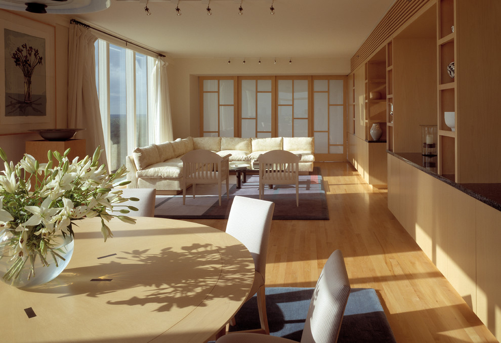 Cette photo montre une petite salle de séjour moderne fermée avec un mur blanc, parquet clair, aucune cheminée, un téléviseur dissimulé et un sol marron.