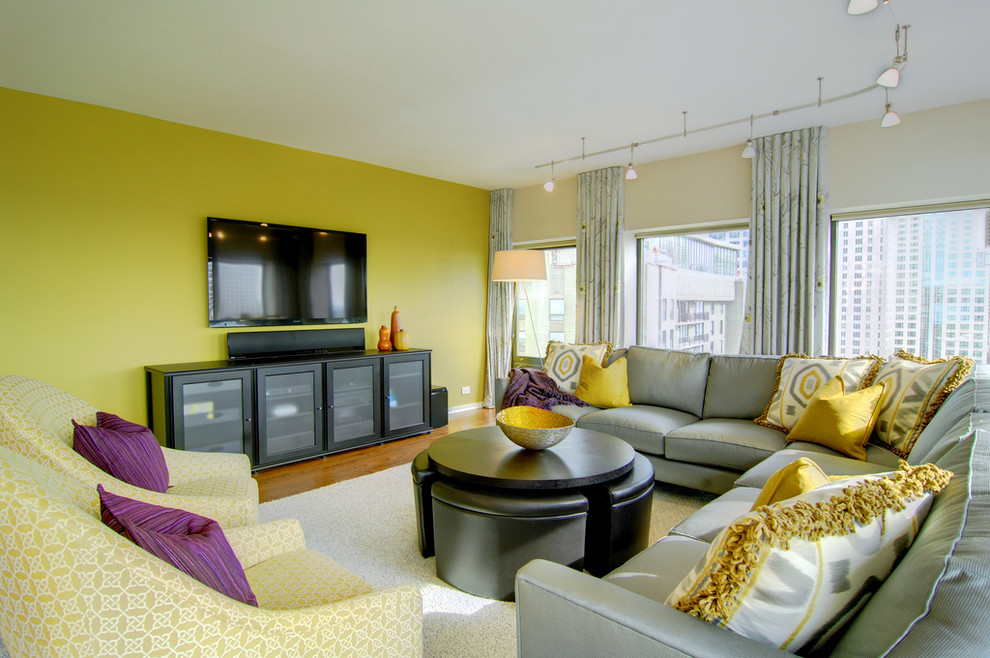Cette image montre une grande salle de séjour design ouverte avec un mur jaune, parquet clair, aucune cheminée et un téléviseur fixé au mur.