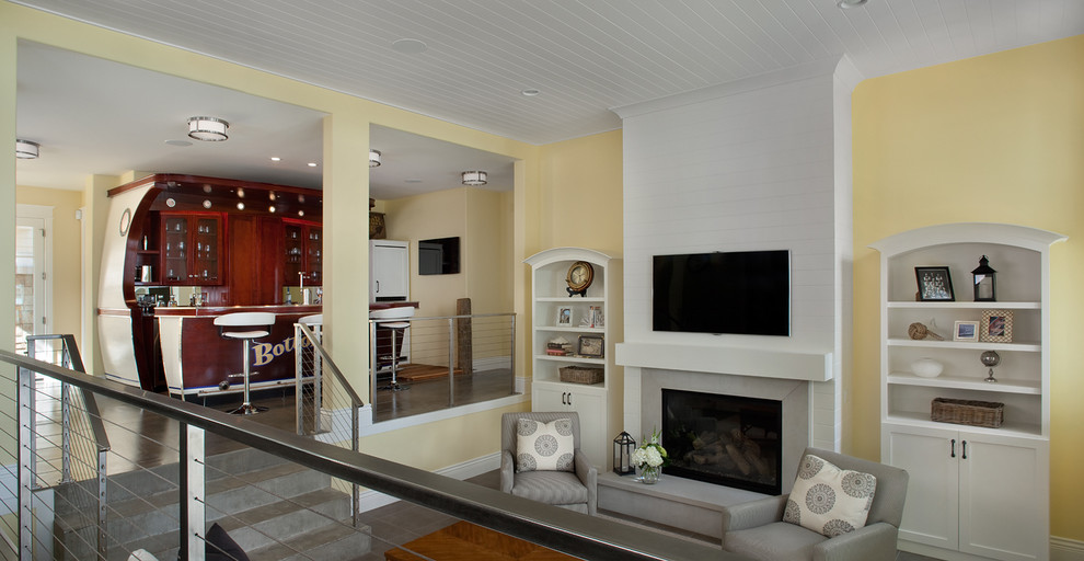Diseño de sala de estar abierta clásica grande con paredes amarillas, todas las chimeneas, marco de chimenea de yeso y televisor colgado en la pared