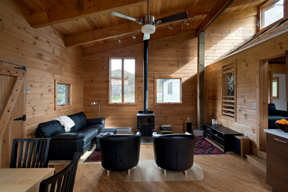 Réalisation d'une petite salle de séjour minimaliste ouverte avec un mur beige, parquet clair, un poêle à bois, un manteau de cheminée en métal, aucun téléviseur et un sol marron.